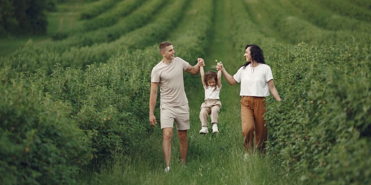 A happy family walking in a lush, green rural field together.